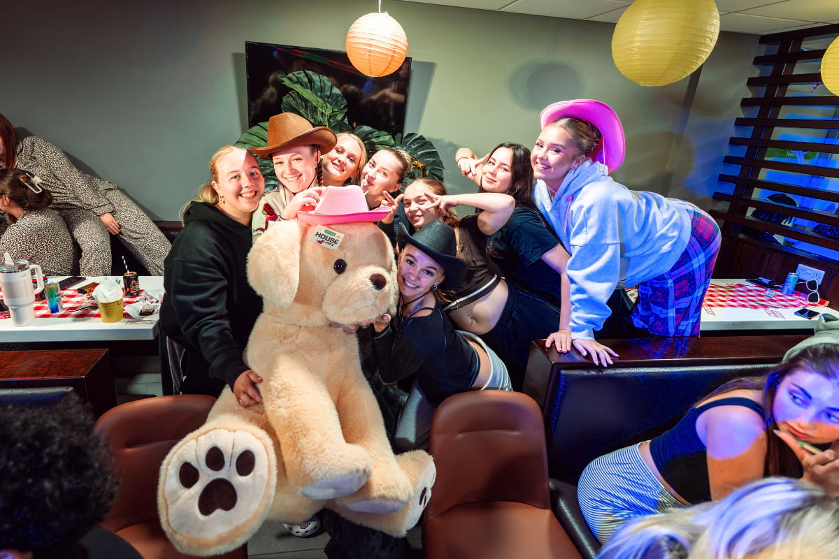female students posing with a large dog toy